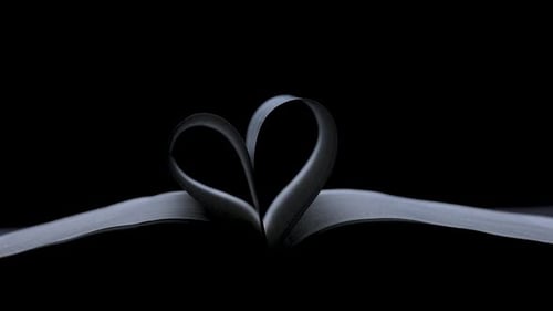 An Open Book Lies in a Dark Studio on a Black Background