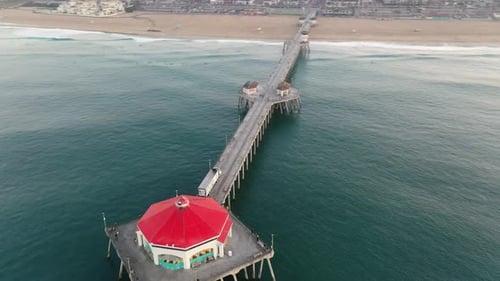 4k Ariel drone clip of the pier in Surf City USA Huntington Beach, California as surfers catch waves