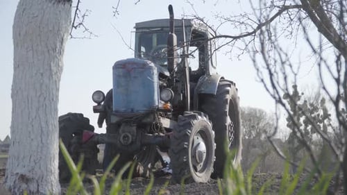 Old Tractor Standing in Rural Field on Sunny Day