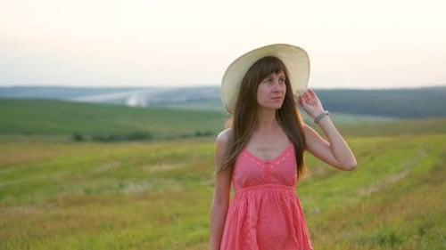 Portrait of Long Haired Young Woman in Red Dress Walking on Green Field Outdoors in Summer