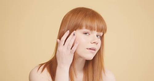 Young Woman with Ginger Hair Checks Blemishes on Face