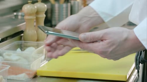 Chef's Male Hands Holding Digital Tablet and Checking the Ingredients