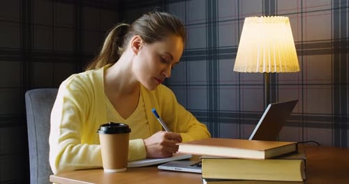 Young Adult Studying with Laptop and Notebook