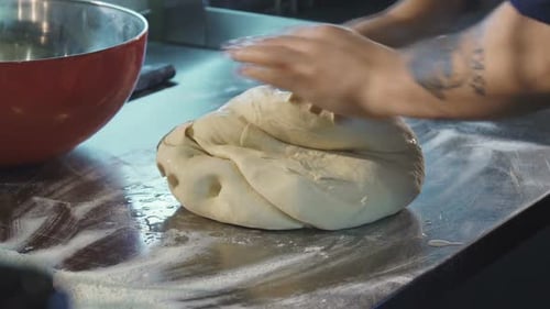 Chef Kneading Dough on a Metal Table