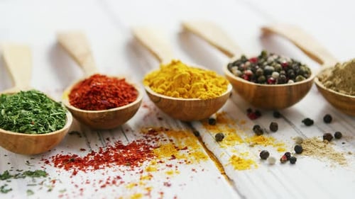Colorful Spices in Wooden Spoons on White Table