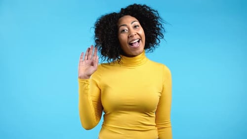 Afrikanische freundliche Frau winkt mit der Hand Hallo