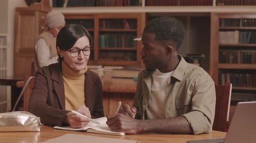 Lecturer and Student Studying in Library