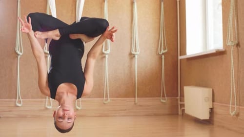 Woman Practices Aerial Yoga in Yoga Studio