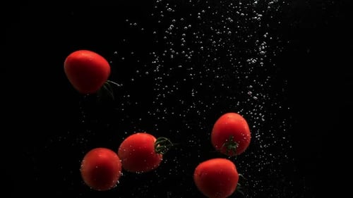 Tomatoes Plunging Into Water on Black Background