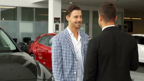 Men Talking and Shaking Hands in Car Dealership