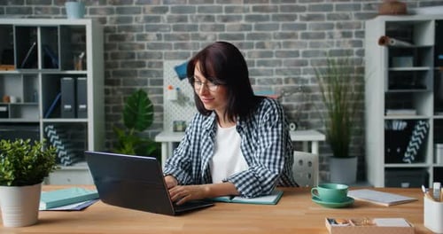 Slow Motion of Attractive Woman Working with Laptop at Desk in Office Alone