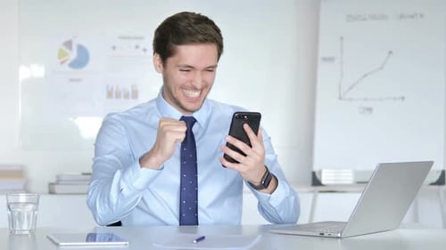 Excited Man Celebrates Good News on Phone at Office