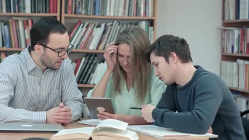 Teacher with Group of Students Working on Digital Tablet in Library