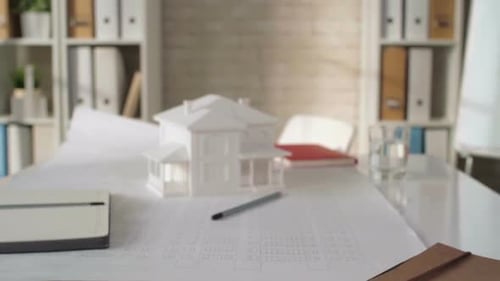 Architectural Plans with White Model House in Office