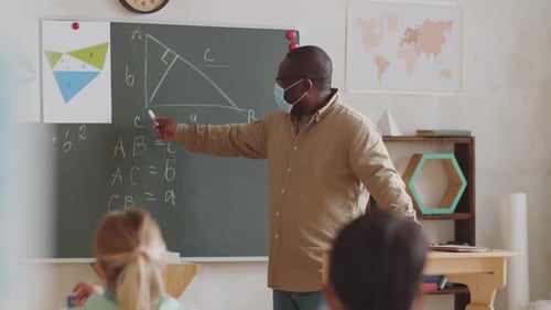 Afro-American Male Teacher in Face Mask Giving Lesson in School