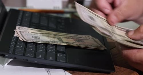 Counting Money on Laptop at a Desk