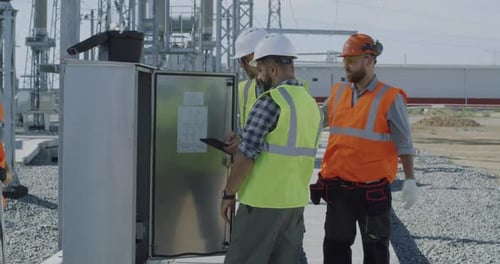 Engineers Inspecting Electrical Equipment at Substation