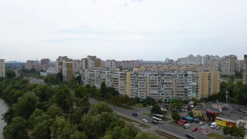 Vista aérea sobre un río, el tráfico en una calle y antiguos edificios de apartamentos, en Troieshchyna, un soviet