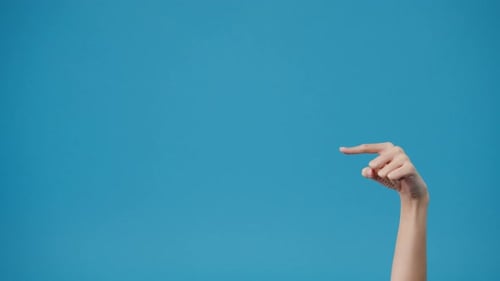 Young woman hand shows something amazing at blank space isolated over blue background in studio.
