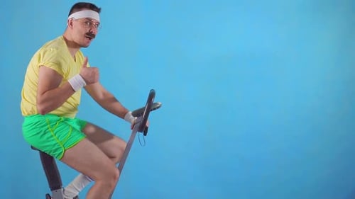 Man with Mustache Rides Exercise Bike, Gives Thumbs Up