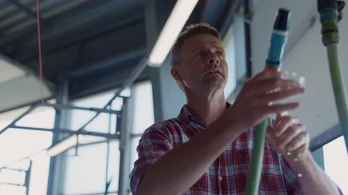Un ouvrier agricole lavant des produits laitiers produisant un automate sur une grange robotique à l'aide d'un tuyau