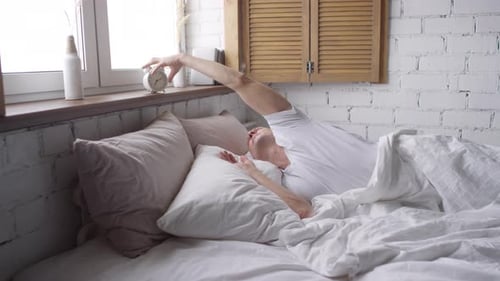 Mann wacht am Wochenende morgens auf und schläft wieder ein