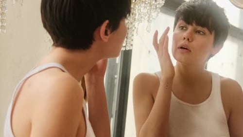 Woman Applies Moisturizer in Mirror at Home