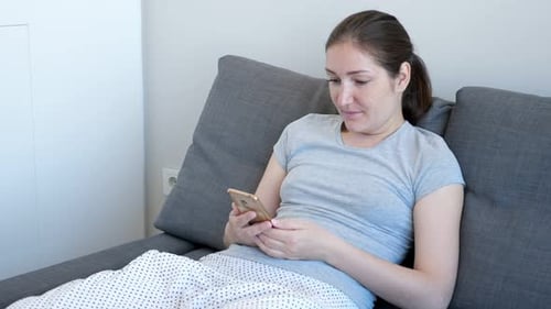 Woman Using Smartphone Relaxing on Couch Indoors
