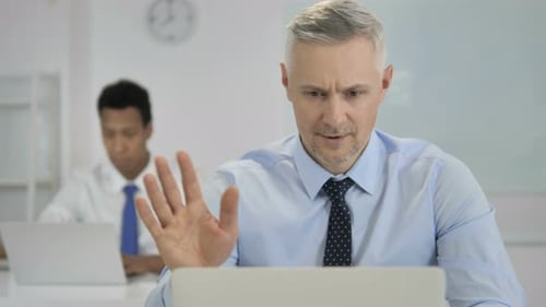 Vídeo chat en línea de un empresario de pelo gris en el trabajo