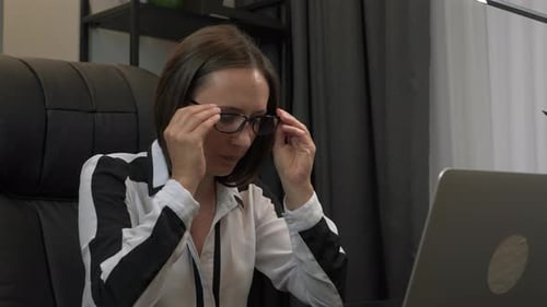 Gestresste junge Frau mit Brille hat aufgrund von Computerüberlastung schmerzhafte Kopfgefühle