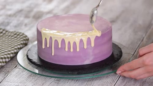 Preparation of a holiday cake. The girl pours liquid white chocolate.