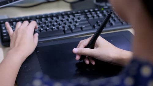 Young Adult Drawing on Tablet at Desk