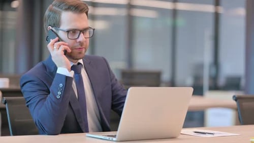 Businessman Talking on Smartphone in Office Setting
