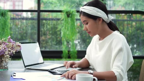 Young Adult Woman Working with Calculator and Laptop