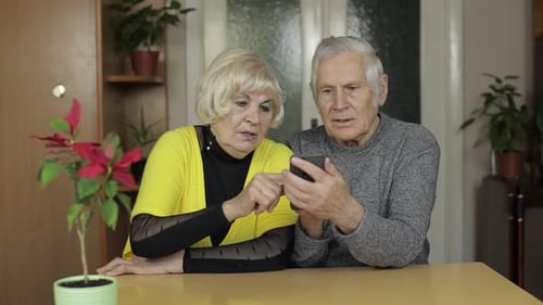 Senior Couple Using Smartphone at Home