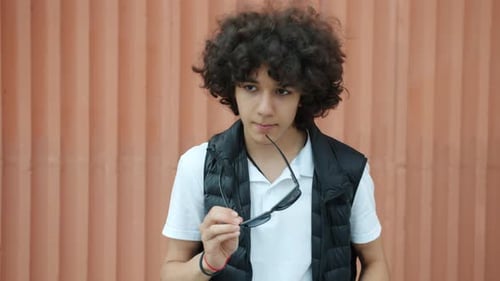 Teen with Curly Hair Puts on Sunglasses