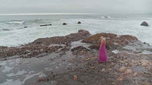 Woman Standing On The Rocky Shore
