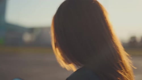 Young Woman Putting On Motorcycle Helmet at Sunset