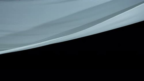 White Sheet Flowing Against Black Background