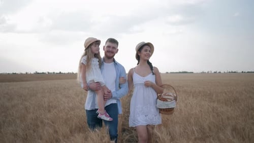 Happy Family with Little Child Girl Talking and Walking on Yellow Wheat Spikelets in Autumn Field