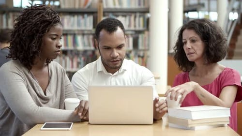 Serious Mature Students Working with Laptop at Public Library