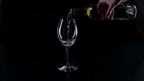 Pouring White Wine into Glass on Black Background