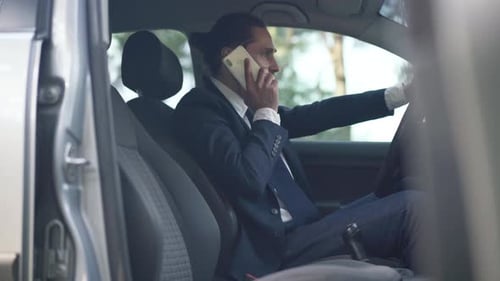 Side View Young Caucasian Man in Suit Arguing Talking on Phone Sitting in Car on Driver's Seat