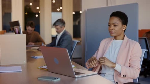 Jeune femme d'affaires multiraciale assise dans un lieu de travail confortable et travaillant avec un ordinateur portable