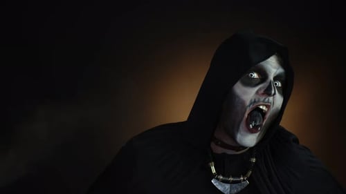 Creepy, Crazy Man with Skeleton Makeup in Hood Making Angry Faces, Shaking Head, Trying To Scare