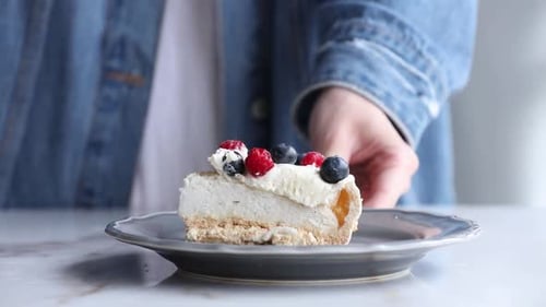 Eating Cheesecake Slice with Berries Using Spoon