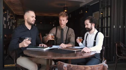 A Group of Three Stylish European Businessman Friends Entrepreneurs in a Cafe
