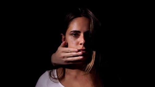 Distressed Woman's Mouth Covered by Hand in Darkness