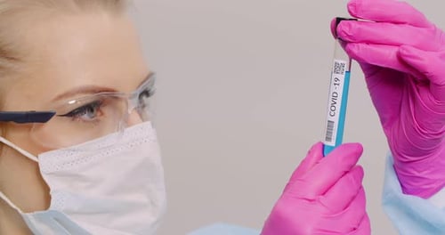 Woman Holds Test Tube Labeled COVID-19