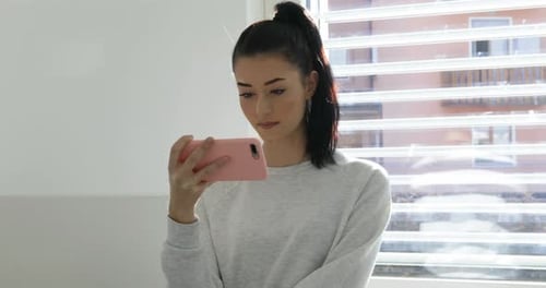 Young Woman Looking at Cellphone Indoors
